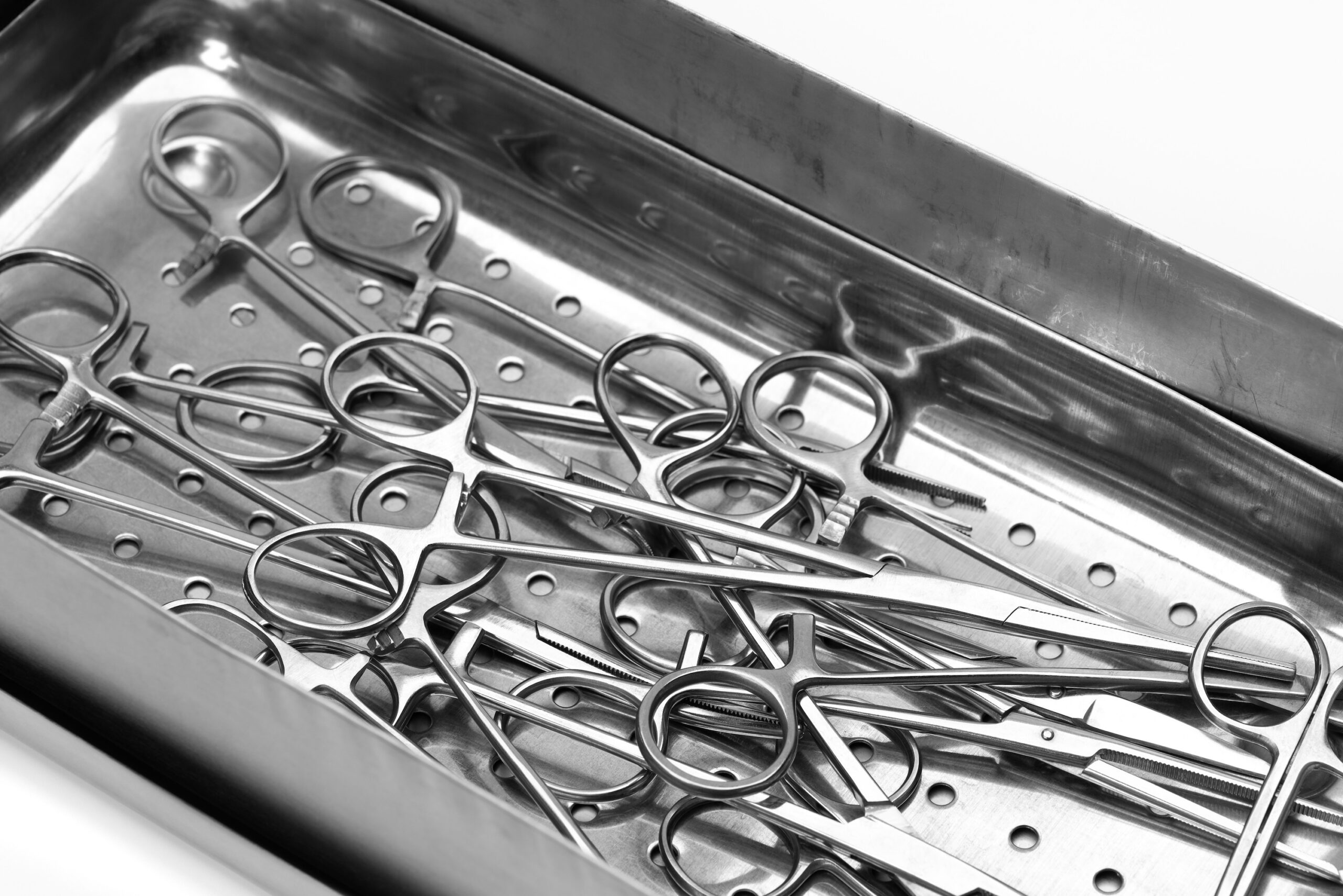 Lot of stainless surgical needle drivers lying on steel tray for